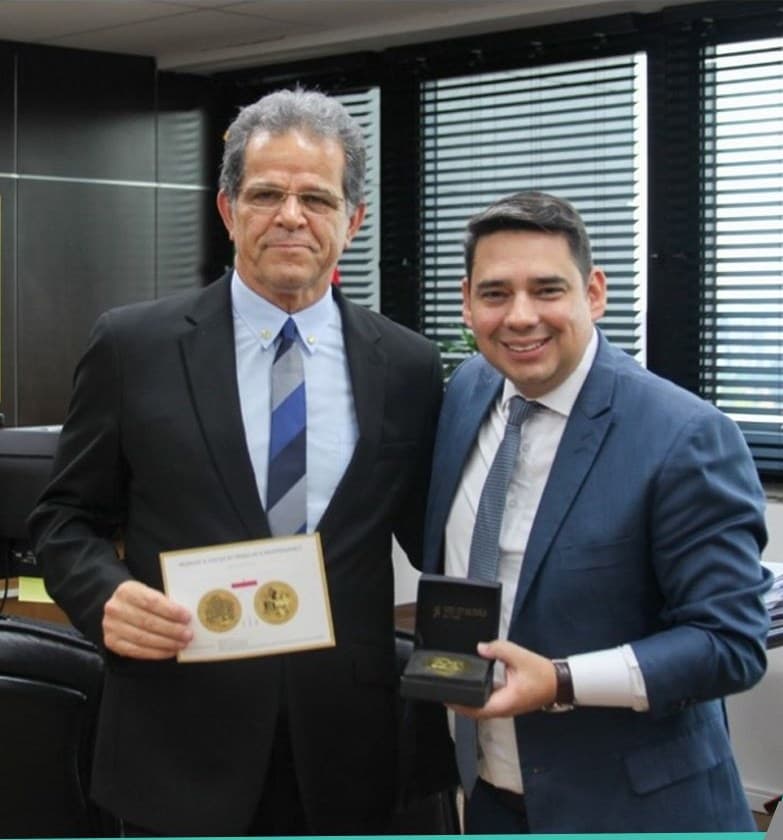 O Desembargador Valdir Florindo e o sócio Abner Vidal lado a lado, segurando a placa e o estojo da Medalha “A Justiça do Trabalho é Indispensável”, do TRT-2.